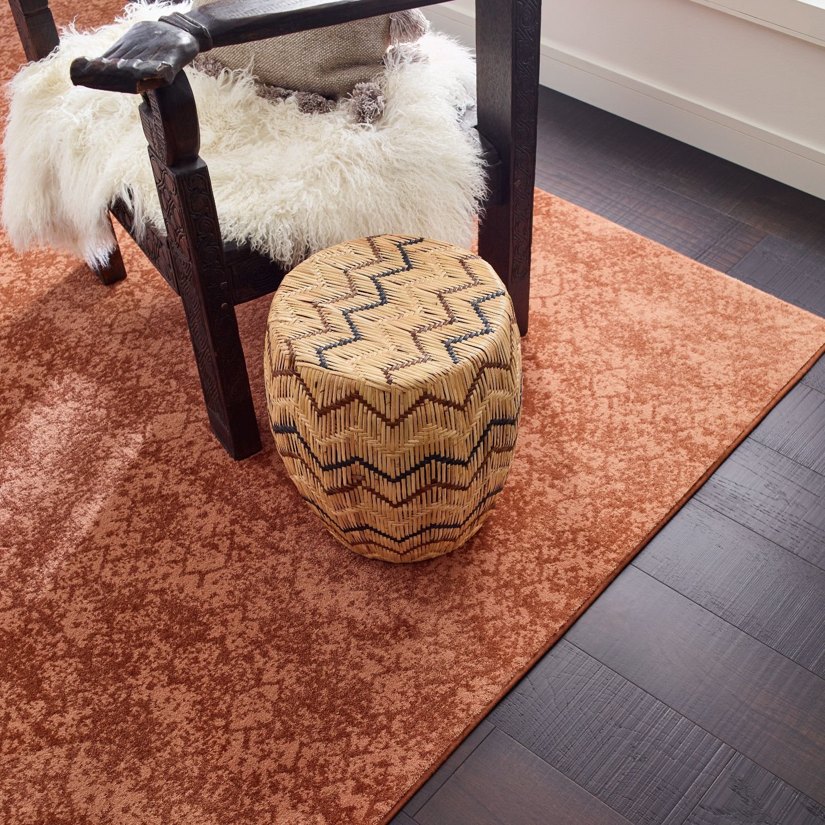 Wooden chair on an orange patterned rug in a room with dark hardwood flooring from Flooring Now in Manassas, VA
